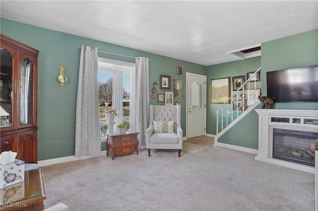 sitting room with a glass covered fireplace, baseboards, and carpet floors