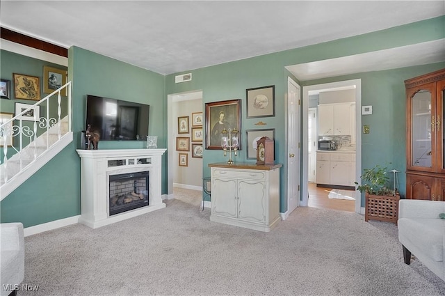 carpeted living area featuring stairs, a fireplace, visible vents, and baseboards