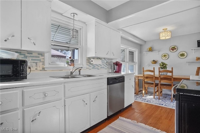 kitchen with wood finished floors, white cabinetry, a sink, black microwave, and stainless steel dishwasher