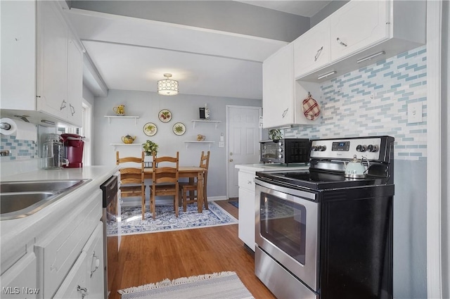 kitchen featuring stainless steel appliances, light countertops, light wood-style floors, white cabinetry, and backsplash