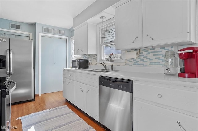 kitchen with visible vents, a sink, stainless steel appliances, light countertops, and white cabinetry