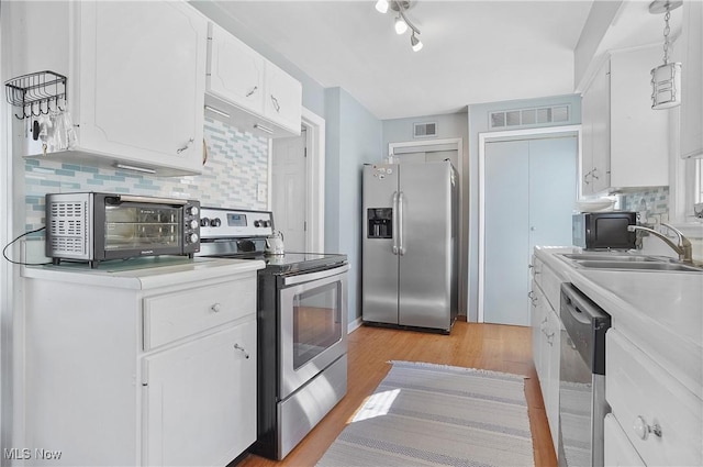 kitchen with light wood-type flooring, stainless steel appliances, light countertops, and a toaster