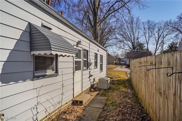 view of property exterior with central AC unit and fence