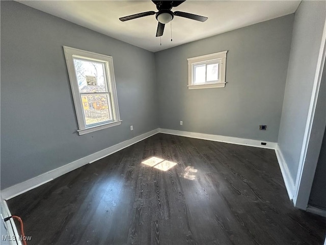 empty room with baseboards, dark wood-type flooring, and ceiling fan