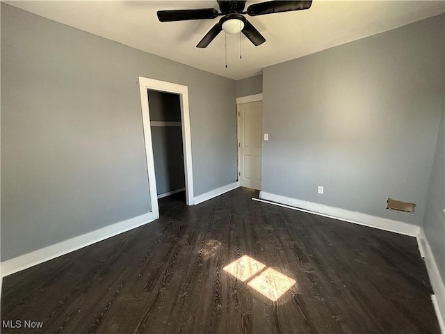 unfurnished bedroom with a closet, baseboards, a ceiling fan, and dark wood-style flooring