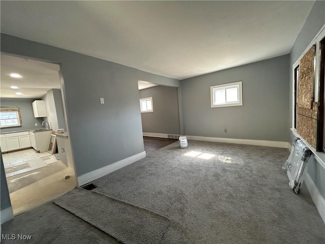 living area featuring visible vents, baseboards, and light carpet