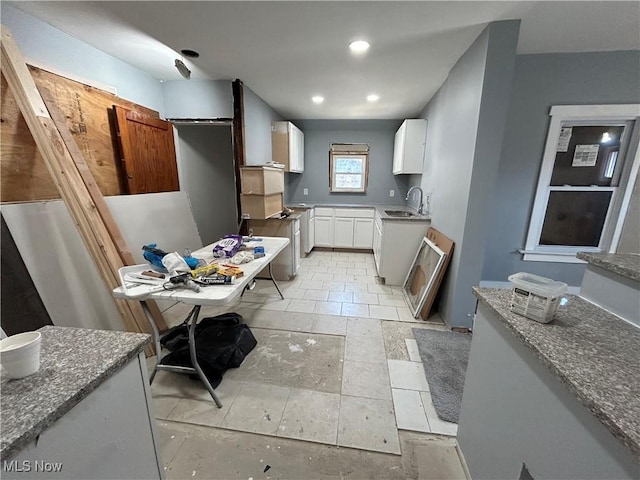 kitchen featuring a sink, stone countertops, white cabinetry, recessed lighting, and stove