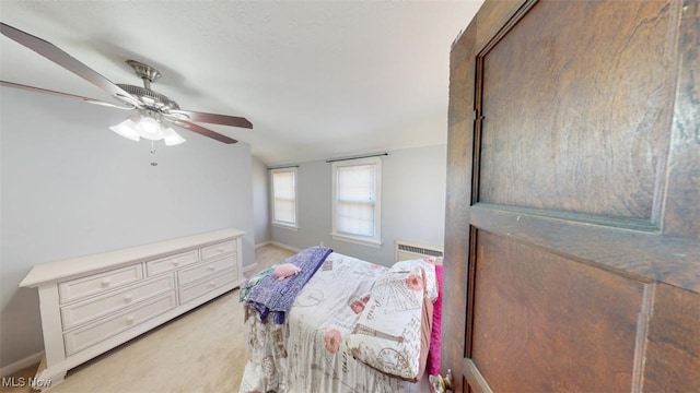 bedroom featuring ceiling fan, baseboards, light colored carpet, radiator heating unit, and lofted ceiling