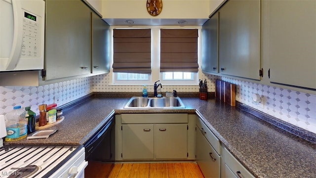 kitchen featuring dark countertops, white microwave, backsplash, black dishwasher, and a sink