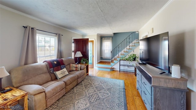 living room with crown molding, stairway, light wood-type flooring, and a textured ceiling