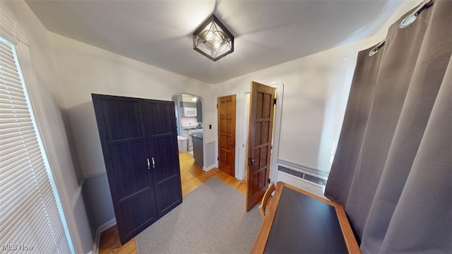 bedroom featuring arched walkways and light wood-type flooring