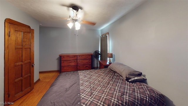 bedroom with light wood-style flooring, a ceiling fan, and baseboards