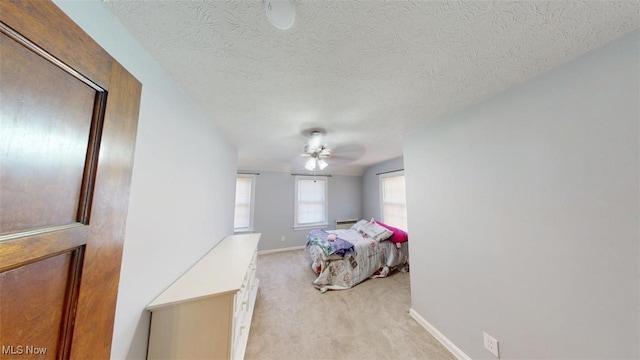 bedroom featuring a textured ceiling, a ceiling fan, baseboards, and light carpet