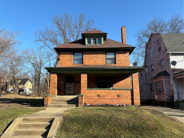 traditional style home with a front lawn, a porch, brick siding, and a chimney