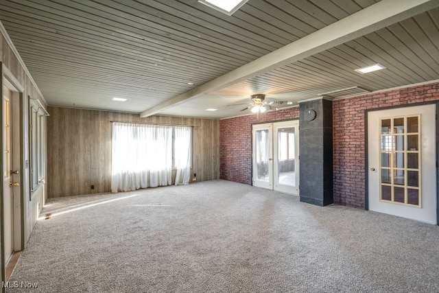 carpeted empty room featuring french doors, beamed ceiling, and brick wall