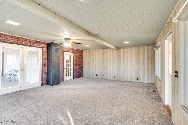 carpeted spare room featuring ceiling fan, beam ceiling, and brick wall