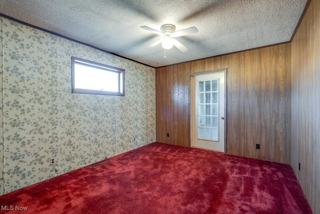 spare room with wallpapered walls, carpet, and a textured ceiling