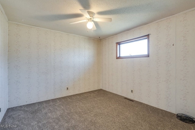 carpeted empty room with visible vents, wallpapered walls, crown molding, a textured ceiling, and a ceiling fan