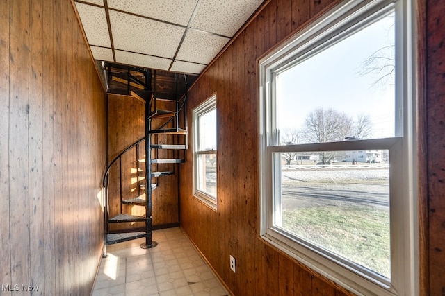 interior space with tile patterned floors, wooden walls, a paneled ceiling, and a wealth of natural light