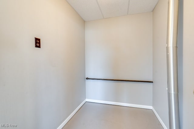 empty room featuring baseboards, a paneled ceiling, and concrete floors