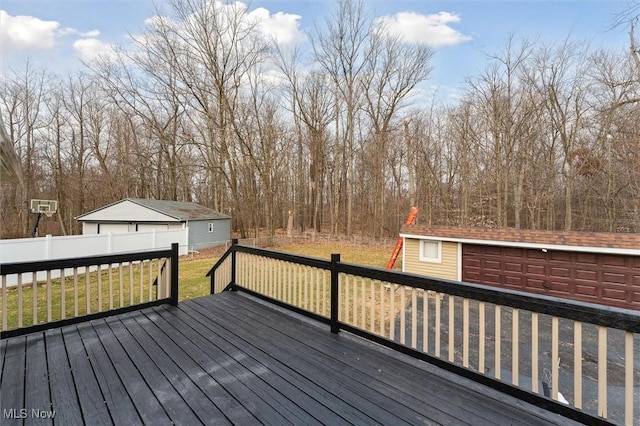 deck featuring an outbuilding, a lawn, a detached garage, and fence