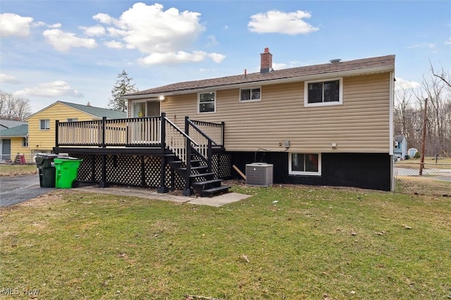 rear view of property featuring a lawn, a deck, fence, central AC unit, and a chimney