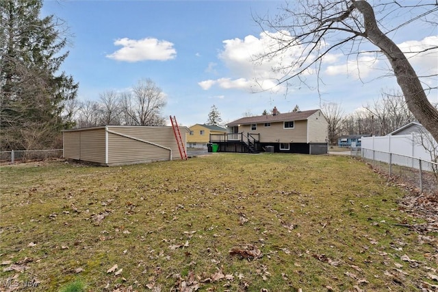 view of yard with a wooden deck, an outbuilding, and a fenced backyard