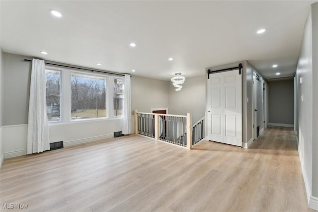 spare room with visible vents, baseboards, recessed lighting, a barn door, and light wood-type flooring