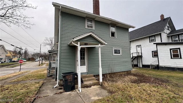 back of property with entry steps and a chimney