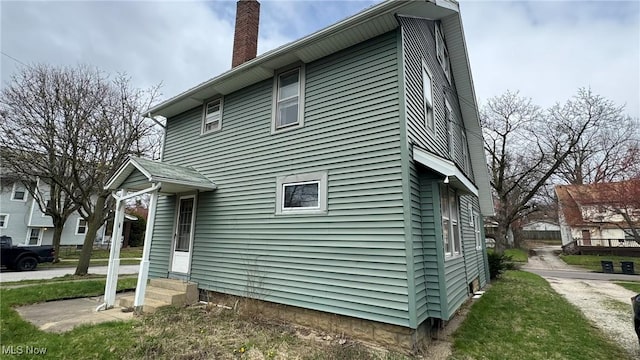 view of property exterior with entry steps and a chimney