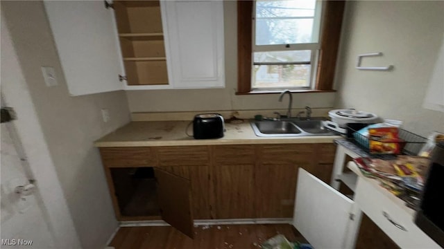 kitchen featuring brown cabinetry, wood finished floors, light countertops, and a sink