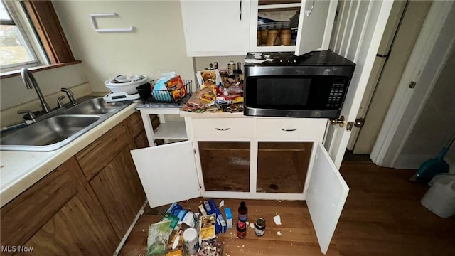 kitchen featuring light countertops, white cabinets, brown cabinets, and a sink