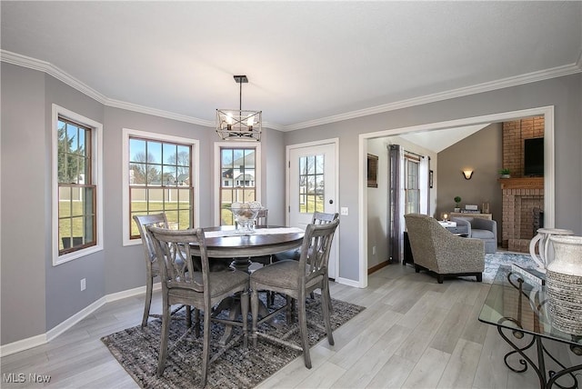 dining space featuring crown molding, baseboards, light wood-type flooring, and a chandelier