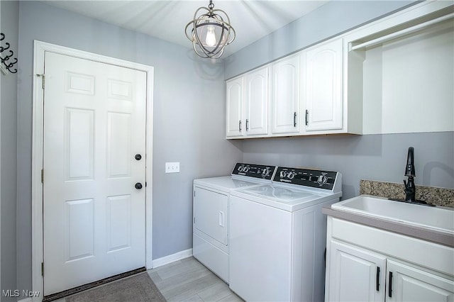 laundry area with light wood-type flooring, independent washer and dryer, a sink, cabinet space, and baseboards