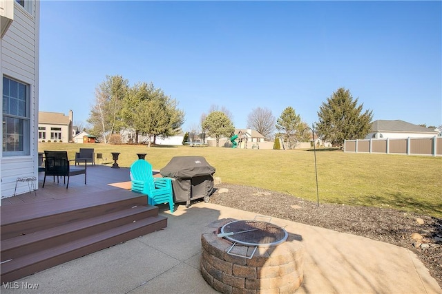 view of patio with area for grilling, a fire pit, a deck, and fence