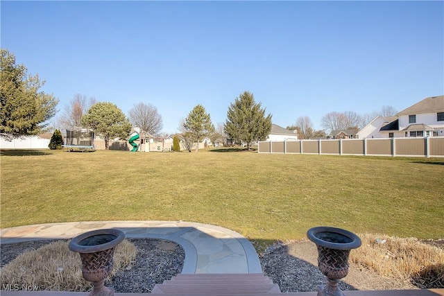 view of yard with a playground, a trampoline, and fence