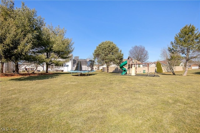 view of yard featuring playground community, a trampoline, and fence