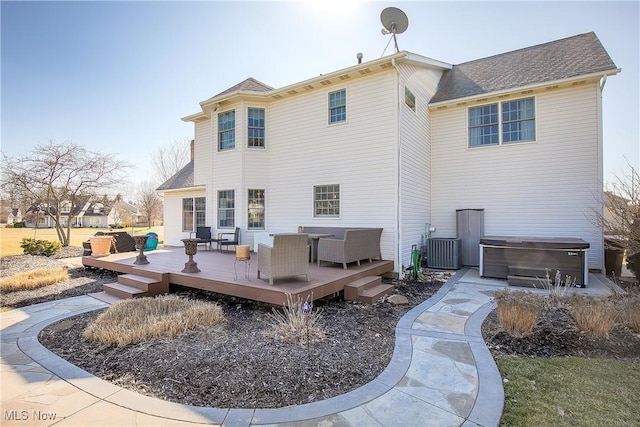 back of property with a wooden deck, a hot tub, and central AC