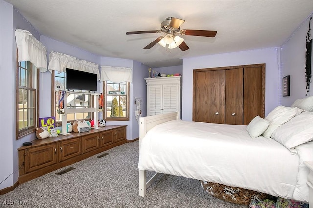 carpeted bedroom with baseboards, visible vents, a closet, and ceiling fan