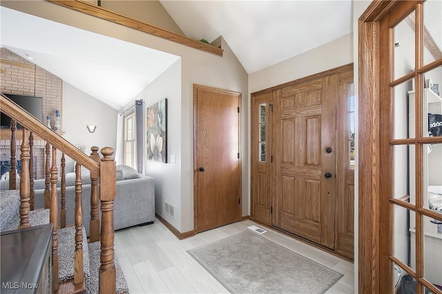 foyer with visible vents, light wood-type flooring, and vaulted ceiling