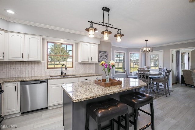 kitchen with a sink, stainless steel dishwasher, white cabinetry, decorative backsplash, and light stone countertops