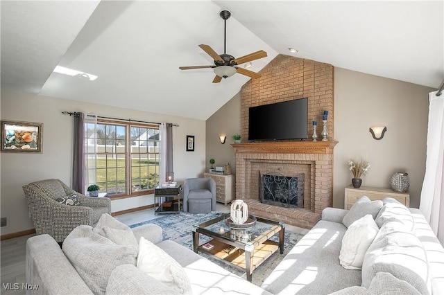 living area with high vaulted ceiling, wood finished floors, baseboards, a brick fireplace, and ceiling fan