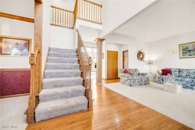 stairway featuring hardwood / wood-style flooring, a high ceiling, and ornate columns