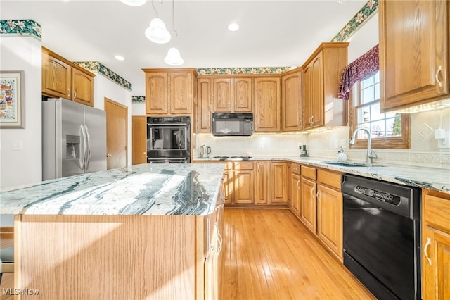 kitchen featuring light stone countertops, a sink, black appliances, pendant lighting, and backsplash