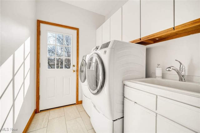 laundry room with a sink, cabinet space, light tile patterned flooring, baseboards, and washing machine and clothes dryer