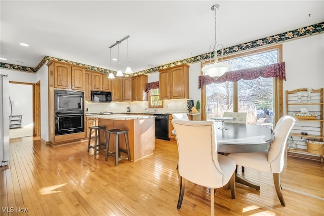 kitchen with black appliances, a center island, light wood finished floors, decorative backsplash, and light countertops