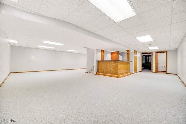 finished basement with a paneled ceiling, baseboards, and stairway