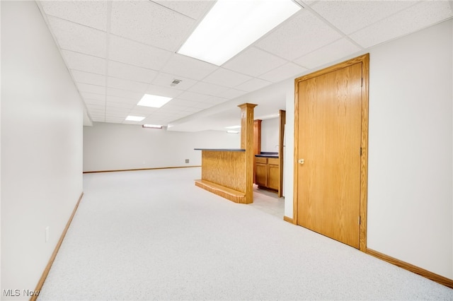 finished basement featuring light carpet, a drop ceiling, visible vents, and baseboards