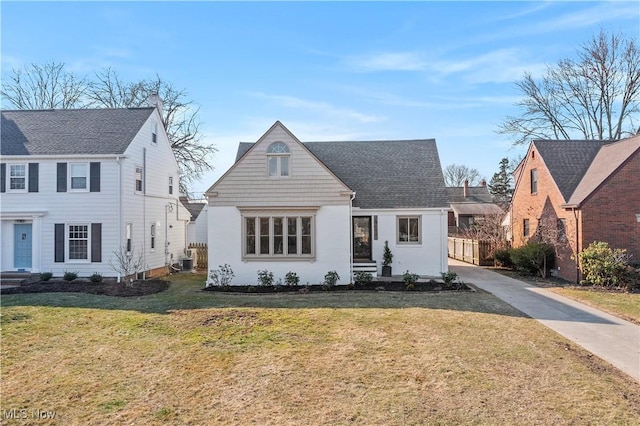 view of front of home with concrete driveway, a front lawn, and a shingled roof