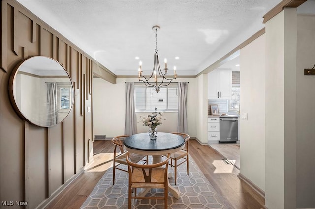 dining space featuring visible vents, crown molding, baseboards, a chandelier, and light wood-style flooring